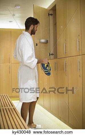 Stock Photo - Man putting his shoes in a locker room at spa. Fotosearch