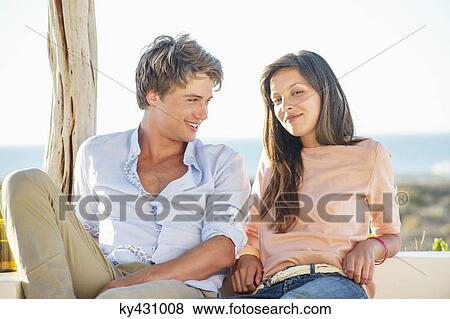 Couple sitting together outdoors on a vacation View Large Photo Image Stock Photo - Couple sitting together outdoors on a vacation. Fotosearch