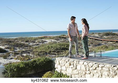 Couple standing on a boardwalk on the beach View Large Photo Image Stock Image - Couple standing on a boardwalk on the beach. Fotosearch