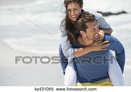 Man giving piggyback ride to his wife on the beach View Large Photo Image Stock Photography - Man giving piggyback ride to his wife on the beach. Fotosearch