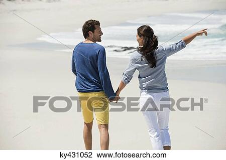 Rear view of a couple walking on the beach View Large Photo Image Stock Image - Rear view of a couple walking on the beach. Fotosearch