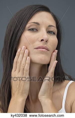 Stock Photo - Portrait of a woman checking wrinkles on her face. Fotosearch