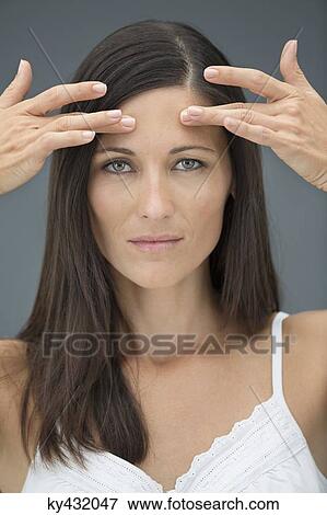 Portrait of a woman checking wrinkles on her forehead View Large Photo Image Stock Photo - Portrait of a woman checking wrinkles on her forehead. Fotosearch