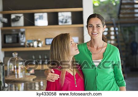 Close-up of a woman smiling with her daughter View Large Photo Image Stock Photo - Close-up of a woman smiling with her daughter. Fotosearch