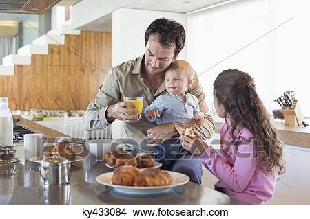 Family having breakfast at a kitchen counter View Large Photo Image Picture - Family having breakfast at a kitchen counter. Fotosearch