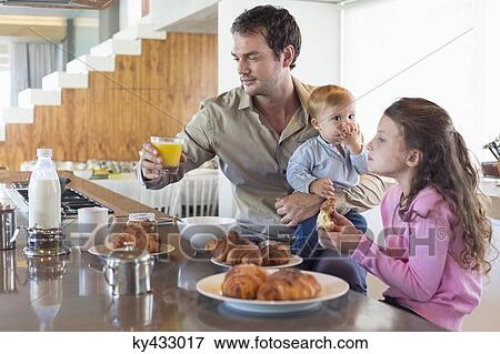 Family having breakfast at a kitchen counter View Large Photo Image Stock Photo - Family having breakfast at a kitchen counter. Fotosearch