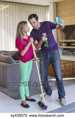 Stock Image - Father and daughter holding cleaning equipment and discussing. Fotosearch