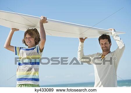 Man and his son carrying a surfboard on the beach View Large Photo Image Stock Photo - Man and his son carrying a surfboard on the beach. Fotosearch