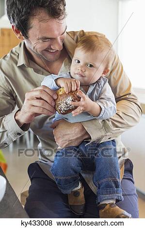 Man feeding bread to his son at a kitchen counter View Large Photo Image Stock Photo - Man feeding bread to his son at a kitchen counter. Fotosearch