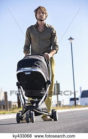 Stock Photo - Man pushing a baby stroller. Fotosearch
