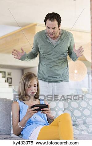 Stock Photography - Man scolding his daughter for playing video game. Fotosearch