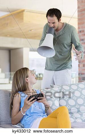 Stock Image - Man shouting into a megaphone at his daughter for playing video game. Fotosearch