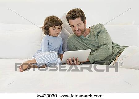 Stock Image - Man showing a digital tablet to his son. Fotosearch