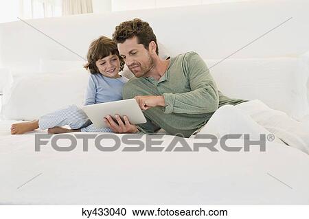 Man showing a digital tablet to his son View Large Photo Image Stock Image - Man showing a digital tablet to his son. Fotosearch