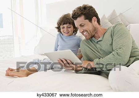Man showing a digital tablet to his son View Large Photo Image Stock Photo - Man showing a digital tablet to his son. Fotosearch