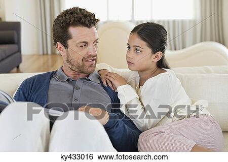 Man sitting with his daughter and reading a magazine View Large Photo Image Stock Photograph - Man sitting with his daughter and reading a magazine. Fotosearch