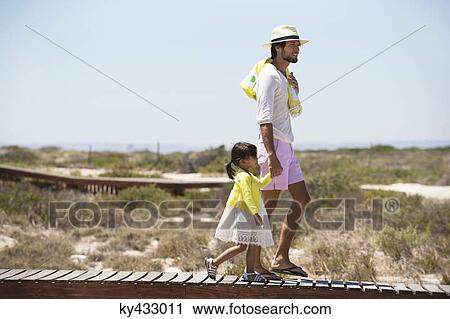 Man with his daughter walking on a boardwalk on the beach View Large Photo Image Stock Image - Man with his daughter walking on a boardwalk on the beach. Fotosearch