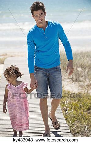 Man with his daughter walking on a boardwalk on the beach View Large Photo Image Stock Photo - Man with his daughter walking on a boardwalk on the beach. Fotosearch