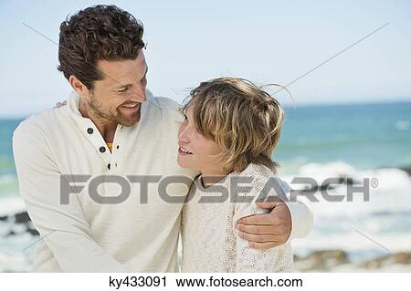 Stock Image - Man with his son smiling on the beach. Fotosearch