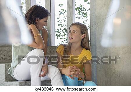 Stock Image - Mother and daughter sitting on steps and talking to each other. Fotosearch