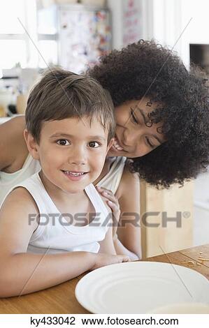 Portrait of a smiling boy sitting with his mother at a dining table View Large Photo Image Stock Image - Portrait of a smiling boy sitting with his mother at a dining table. Fotosearch