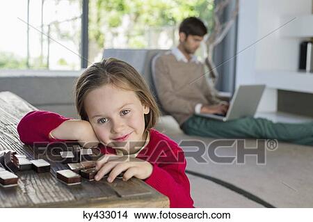 Portrait of a smiling girl with her father using a laptop in the background View Large Photo Image Picture - Portrait of a smiling girl with her father using a laptop in the background. Fotosearch