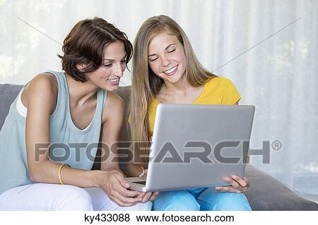 Stock Photo - Smiling mother and daughter looking at a laptop. Fotosearch