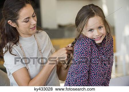 Smiling woman braiding her daughter's hair View Large Photo Image Stock Photo - Smiling woman braiding her daughter's hair. Fotosearch