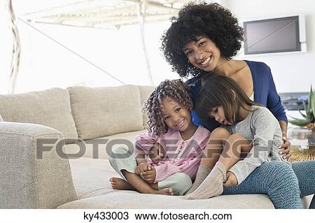 Smiling woman sitting with her two daughters View Large Photo Image Stock Image - Smiling woman sitting with her two daughters. Fotosearch