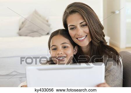 Woman and her daughter looking at a digital tablet View Large Photo Image Stock Photograph - Woman and her daughter looking at a digital tablet. Fotosearch