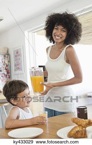 Woman and her son at a dining table with orange juice View Large Photo Image Stock Photo - Woman and her son at a dining table with orange juice. Fotosearch