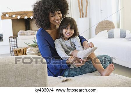 Woman putting on socks to her daughter and smiling View Large Photo Image Picture - Woman putting on socks to her daughter and smiling. Fotosearch