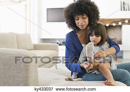 Woman putting on socks to her daughter and smiling View Large Photo Image Stock Photo - Woman putting on socks to her daughter and smiling. Fotosearch