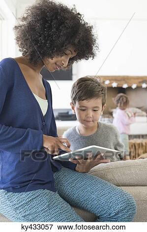 Woman showing a digital tablet to her son View Large Photo Image Stock Photo - Woman showing a digital tablet to her son. Fotosearch