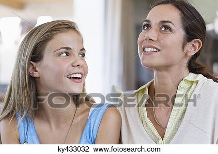 Stock Image - Woman smiling with her daughter at home. Fotosearch