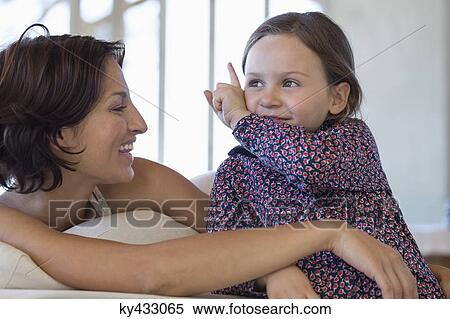 Stock Photography - Woman smiling with her daughter at home. Fotosearch