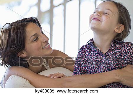 Stock Photography - Woman smiling with her daughter at home. Fotosearch
