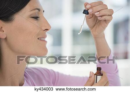 Stock Image - Close-up of a woman taking homeopathic medicine. Fotosearch