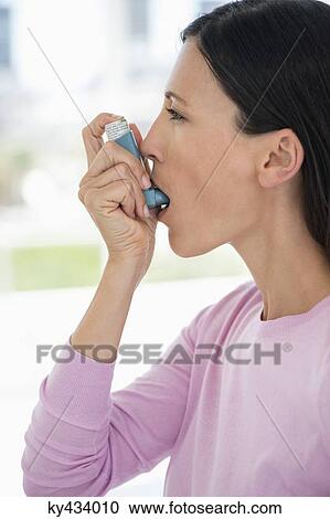 Stock Image - Close-up of a woman using an asthma inhaler. Fotosearch