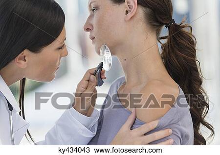 Dermatologist using magnifying glass to examine woman's skin View Large Photo Image Stock Image - Dermatologist using magnifying glass to examine woman's skin. Fotosearch