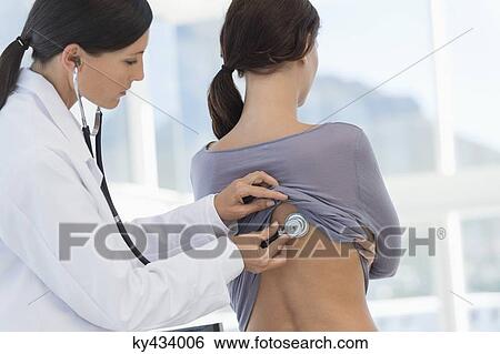 Female doctor examining a woman's back with a stethoscope View Large Photo Image Stock Photograph - Female doctor examining a woman's back with a stethoscope. Fotosearch
