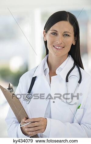 Female doctor holding a clipboard and smiling View Large Photo Image Stock Photo - Female doctor holding a clipboard and smiling. Fotosearch