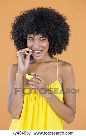Portrait of a smiling woman eating a capsule View Large Photo Image Stock Photo - Portrait of a smiling woman eating a capsule. Fotosearch