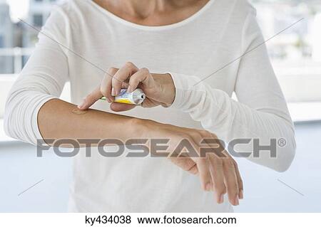 Stock Photo - Woman applying ointment on her arm. Fotosearch