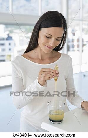 Woman dropping liquid medicine into water View Large Photo Image Picture - Woman dropping liquid medicine into water. Fotosearch