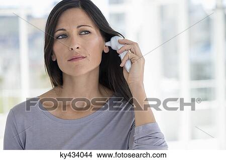Woman measuring her temperature with a digital thermometer View Large Photo Image Picture - Woman measuring her temperature with a digital thermometer. Fotosearch