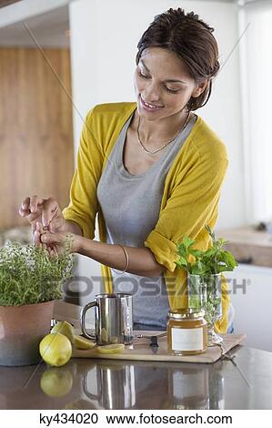 Woman preparing herbal tea in the kitchen View Large Photo Image Stock Image - Woman preparing herbal tea in the kitchen. Fotosearch