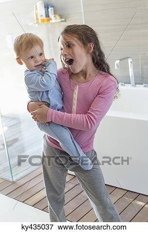 Girl carrying her brother and looking surprised in a bathroom View Large Photo Image Stock Photo - Girl carrying her brother and looking surprised in a bathroom. Fotosearch