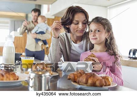 Girl having breakfast beside her mother at a kitchen counter View Large Photo Image Picture - Girl having breakfast beside her mother at a kitchen counter. Fotosearch