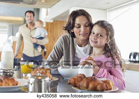 Girl having breakfast beside her mother at a kitchen counter View Large Photo Image Stock Photo - Girl having breakfast beside her mother at a kitchen counter. Fotosearch